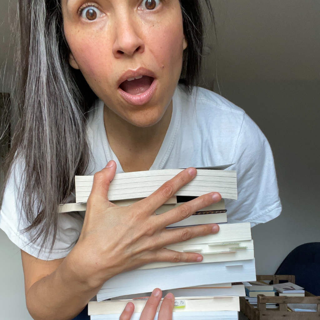 Female holding several books in her hands with a surprised look on her face.