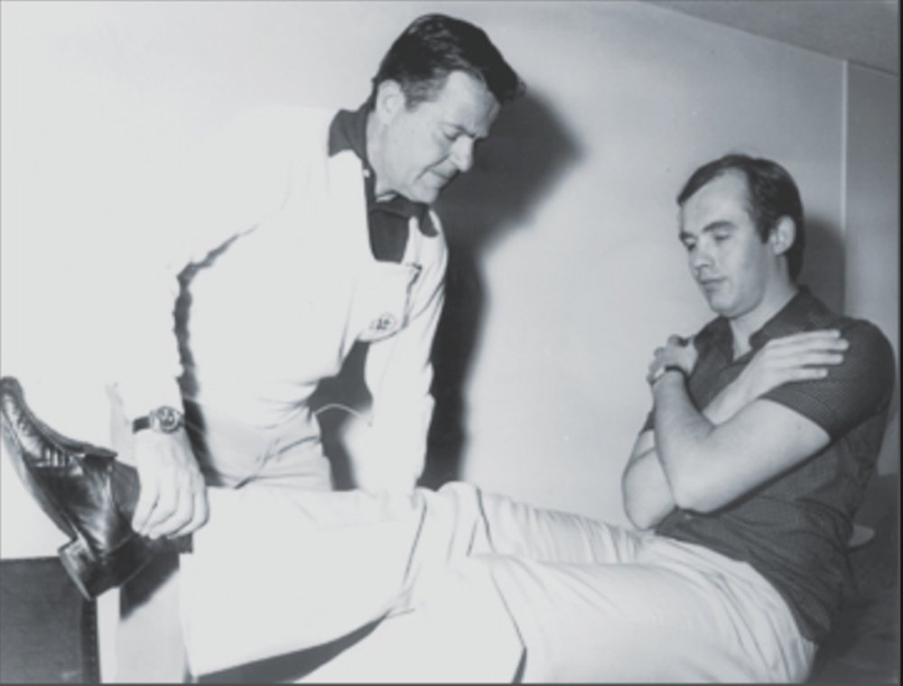 Picture of George Goodheart applying muscle testing on a patient.