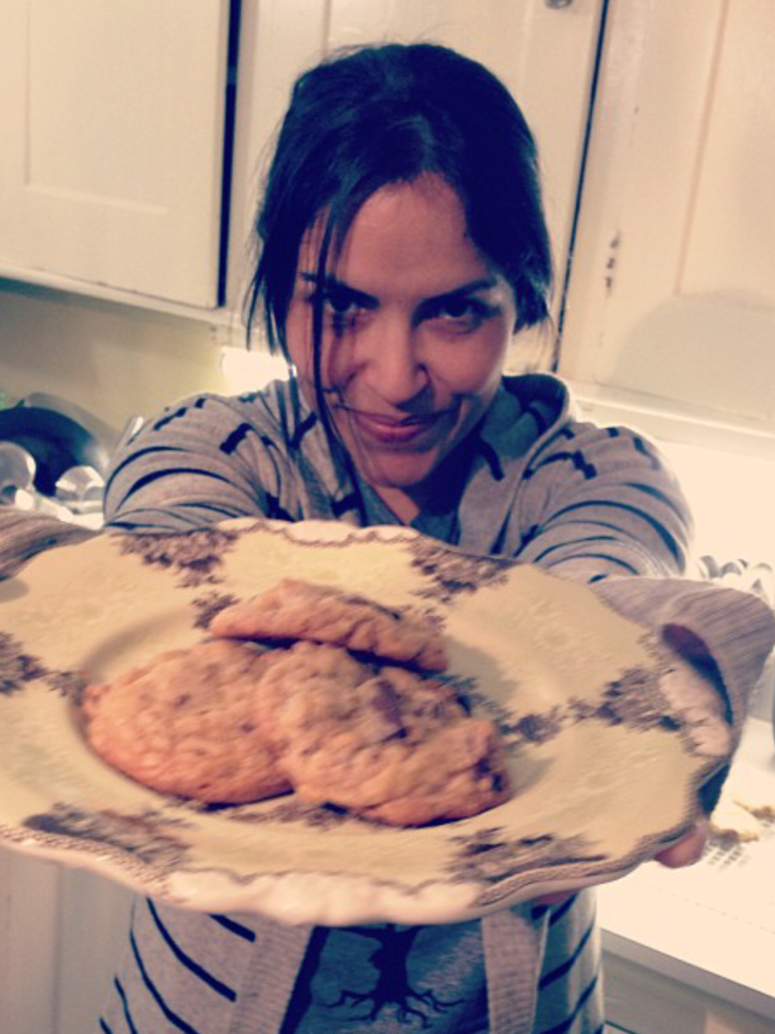 A female holding up a plate of cookies towards the camera.