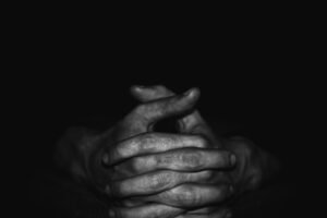 Black and white photo of hands clasped as if praying.