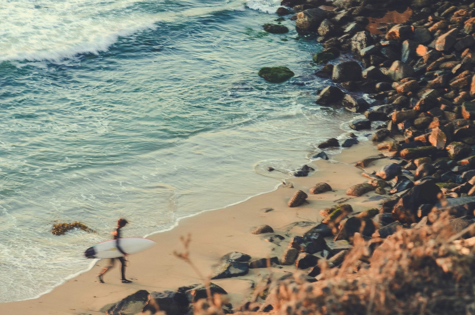 Image of a surfer walking out of the ocean to the shore